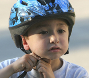 Photo of a child putting on a bicycle helmet.